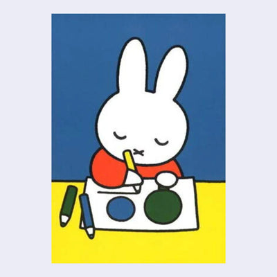 Illustration on a postcard of Miffy, sitting at a yellow desk and drawing shapes onto a piece of paper with her eyes closed. Background is blue.