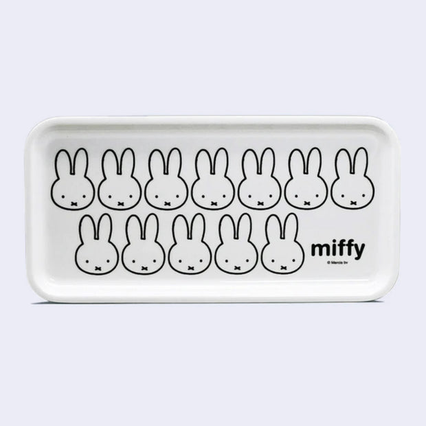 White rectangular tray with a repeating design of Miffy's face, with her small eyes and x shaped mouth. In the lower right corner reads "miffy".