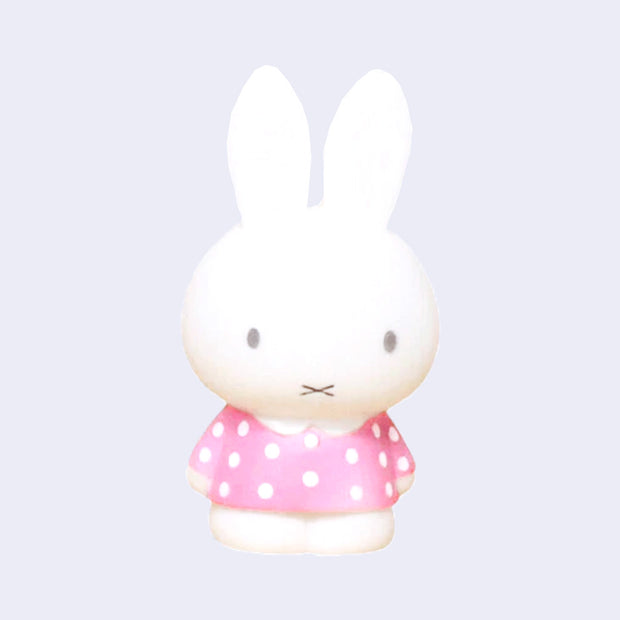 Figurine of Miffy standing with her arms at her side, wearing a pink dress with white polka dots.