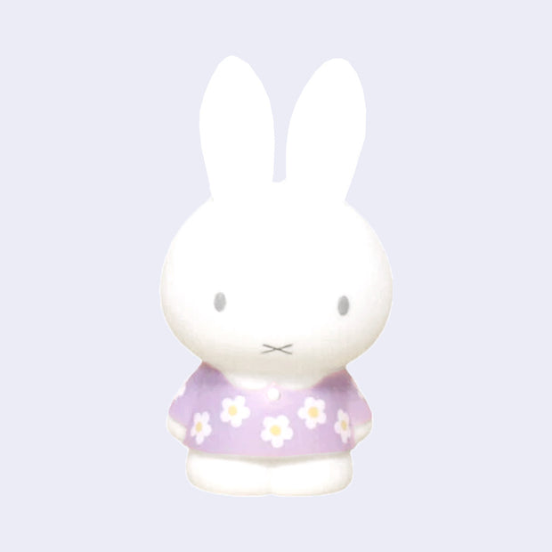 Figurine of Miffy standing with her arms at her sides while wearing a purple floral patterned dress with white flowers.