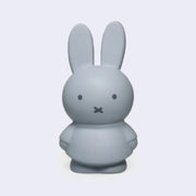 Miffy shaped coin bank, completely colored a silver shade of blue with gray eyes and mouth. She stands wearing a dress with her arms at her sides.