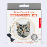 Product packaging for a mini cross stitch embroidery kit with the design of a gray tabby cat with green eyes, only its head is visible.