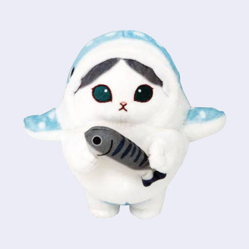 Plush doll of a gray and white cat with large teal eyes and a small mouth. It wears a blue spotted shark costume and holds a gray striped fish.