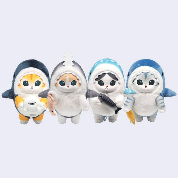 4 keychains of plush cat dolls with large, cute eyes and small mouths. They each wear a shark costume and hold a sea creature, such a seal, a fish, a squid, etc.