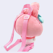 Plush doll of My Melody, made into a backpack with a zip top and adjustable pink straps. Her facial features are embroidered on and she has floppy ears and a blue bow. Back view.