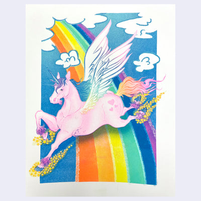 Colorful risograph print of a pink unicorn flying over a rainbow against a blue cloudy sky.