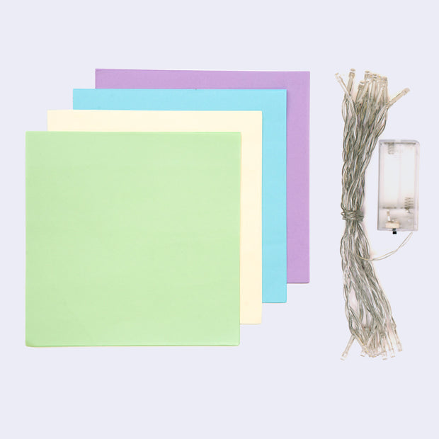 4 sheets of pastel square sheets of paper with a row of string lights.