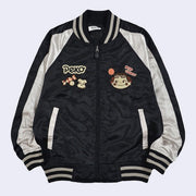 Shiny black bomber jacket with white sleeves and small embroideries on the chest of Peko Chan, a smiling girl with rosy cheeks and candy accessories.