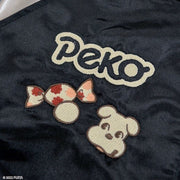 Close up detail, showing embroidery on jacket lapel of "Peko" in stylized font, a small dog and a piece of candy.