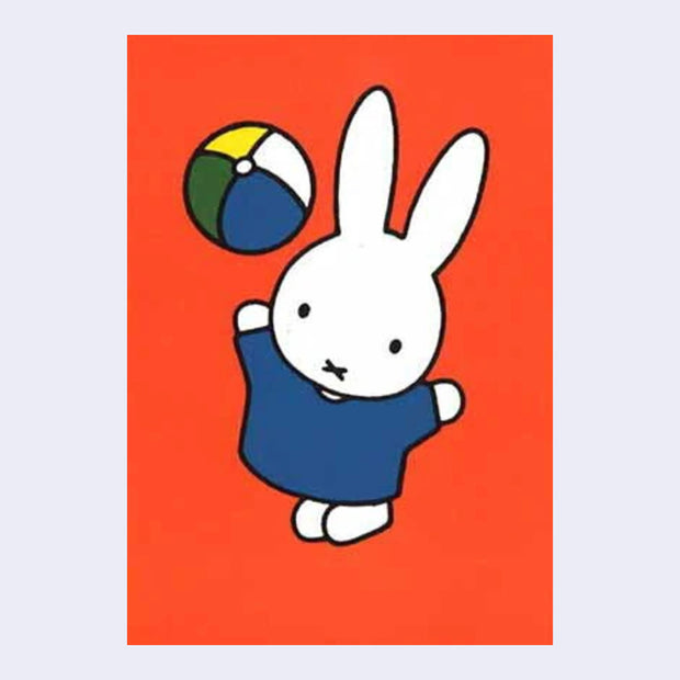 Reddish orange background postcard of Miffy wearing a blue dress and playing with a multicolor ball, throwing it in the air.