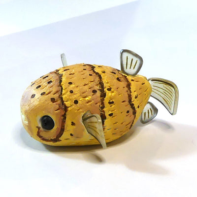 Clay sculpture of a yellow and brown puffer fish, with semi transparent fins and large black eyes. 