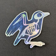 A die-cut sticker of a black bird (maybe a small crow) that looks like it's being run through an X-ray machine. metallic holographic sheen.