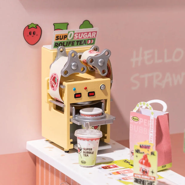 Detail shot of 3D diorama kit of a bubble tea shop, showing a counter with a cup label machine.