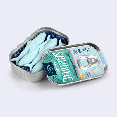 Tin made to look like a sardine tin, with a pop off tab lid and mock packaging design on the front. Inside are 4 pale blue erasers shaped like sardines, packed together closely.