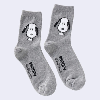 Pair of gray socks with a graphic of Snoopy, looking straight at the viewer and seen only from the neck up.