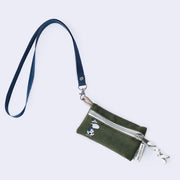 Small green canvas pouch with a zip closure, featuring a small illustration in the left corner of Snoopy wearing his hiking gear - a green hat and a blue backpack. It is attached to a blue fabric lanyard.