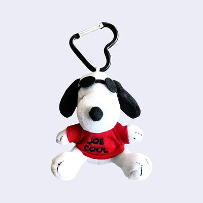 Plush doll of Snoopy wearing sunglasses with a red shirt that reads "Joe Cool". He sits and is attached to a heart shaped keyring.