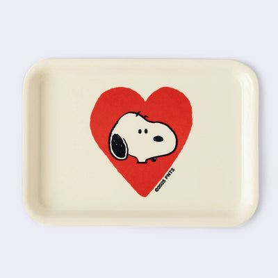 Cream colored rectangle shaped tray with a slight lip. In the center is a graphic of Snoopy's head, with a plain expression. He head is encased in a red heart.