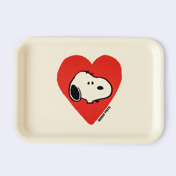 Cream colored rectangle shaped tray with a slight lip. In the center is a graphic of Snoopy's head, with a plain expression. He head is encased in a red heart.