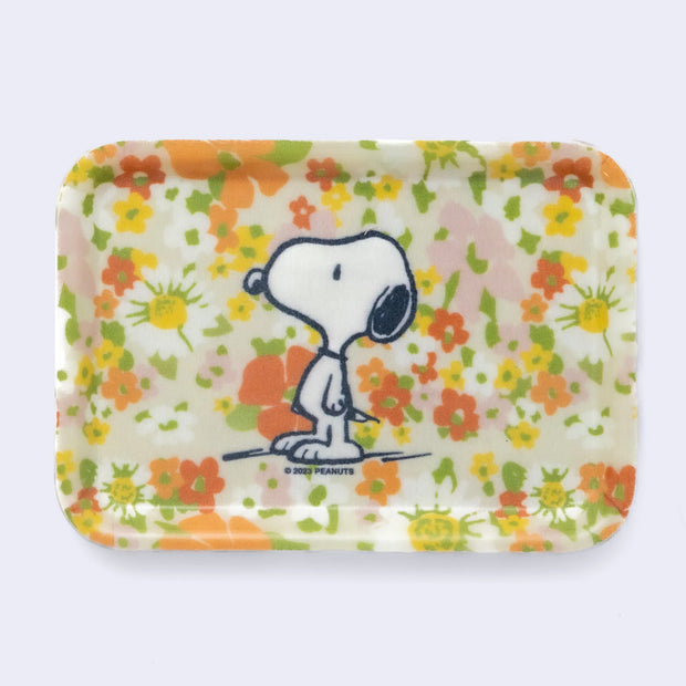 Retro style trinket tray, with a orange, yellow and pink floral design reminiscent of the 70's with a graphic of Snoopy on it.