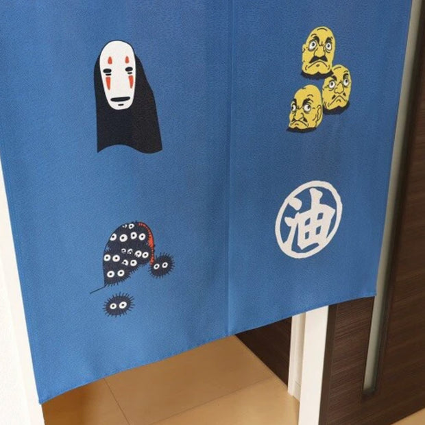 Close up of tapestry detail, blue with illustrated icons from Spirited Away, such as characters and symbols.