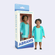 Action figure of politician Stacey Abrams, wearing a bright teal blue blazer and matching dress with black heels and a necklace. She smiles warmly.