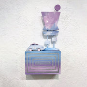 Small rectangular wooden box painted like a blue and purple sunset with a silver line pattern. Atop of it are 2 wooden sculptures: a retro car and a large signage.