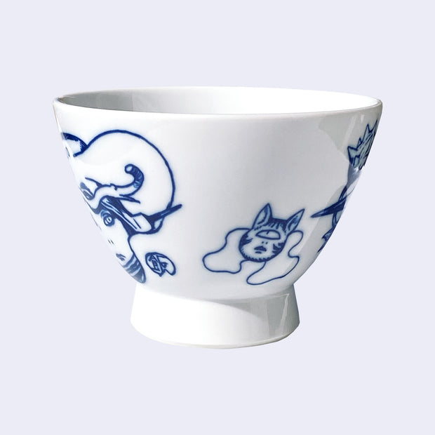 White ceramic bowl with a large rounded base that extends out slightly. A dark blue line illustration of the side of a girl's face and a small one eyed cat head is on the bowl. The cat looks up with its mouth slightly ajar.