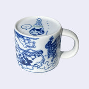 Underside of white porcelain mug, with a graphic of a one eyed stripe cat head with a speech bubble that reads "hot!".