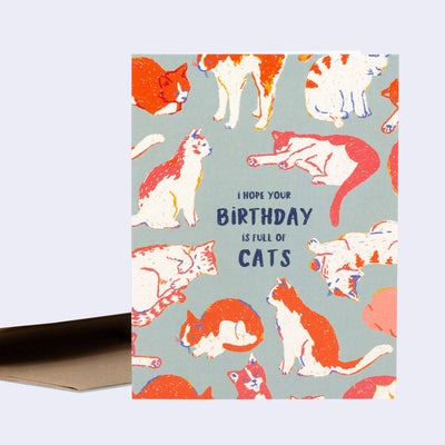 Greeting card, a muted greenish gray with illustrations of many white and orange cats, laying down or sitting in restful manners with text in the center that reads "I Hope Your Birthday is Full of Cats".