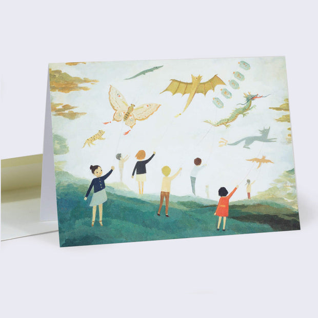 Horizontal greeting card with a full bleed illustration of many children standing in a meadow, all holding up elaborately shaped animal kites.