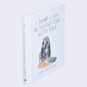 Side angle of "I Think I Am in Friend Love With You",  all white with thin title font and an illustration of a one eyed hairy monster holding a cup of coffee at a table.