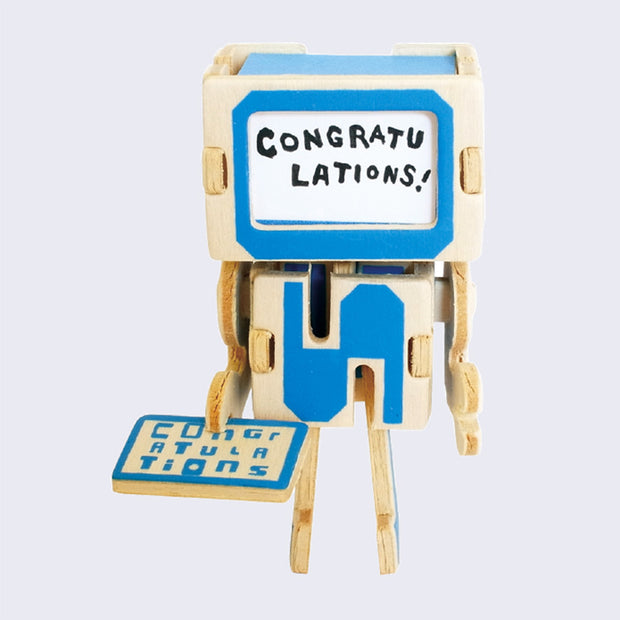 Robot face has been replaced with tiny paper card that has example text that says congratulations in blank ink.