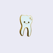 Side angle of enamel pin of an illustrated smiling white tooth with gold sparkles in the top right corner and a gold outline.