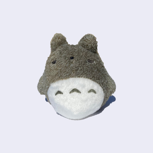 Small Totoro plush with its eyes closed, as if sleeping.