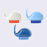 3 plastic cartoon whales, with semi circle bodies and a wide tail curved upward. They each have soft bristled brushes attached to their underside, for brushing nails or cleaning hands. Colors are: white with orange, light blue, or dark blue.